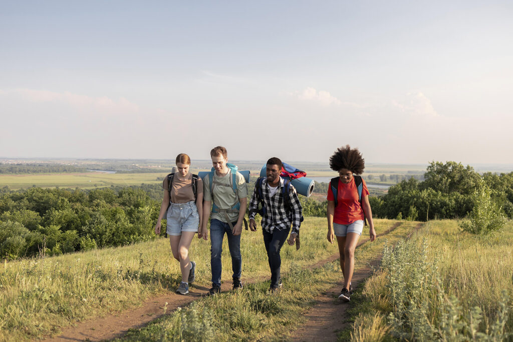 A group of friends hiking through a scenic mountain trail, with backpacks and outdoor gear, enjoying the natural beauty around them.