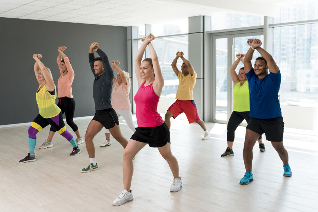 A group of people participating in a Zumba class, dancing energetically to vibrant music, and enjoying the workout.