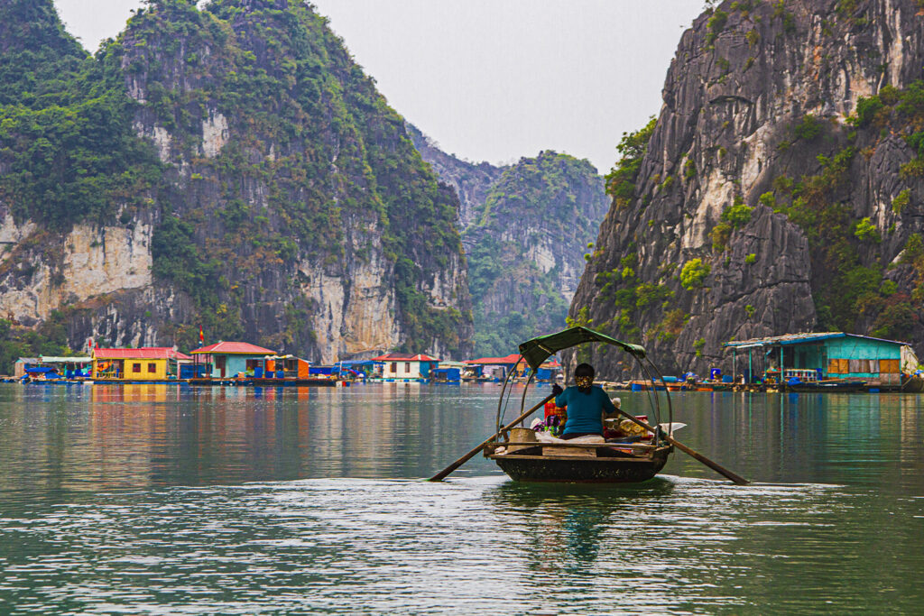 A vibrant landscape of Ha Long Bay in Vietnam, featuring turquoise waters, lush limestone karsts, and traditional wooden boats gliding peacefully.