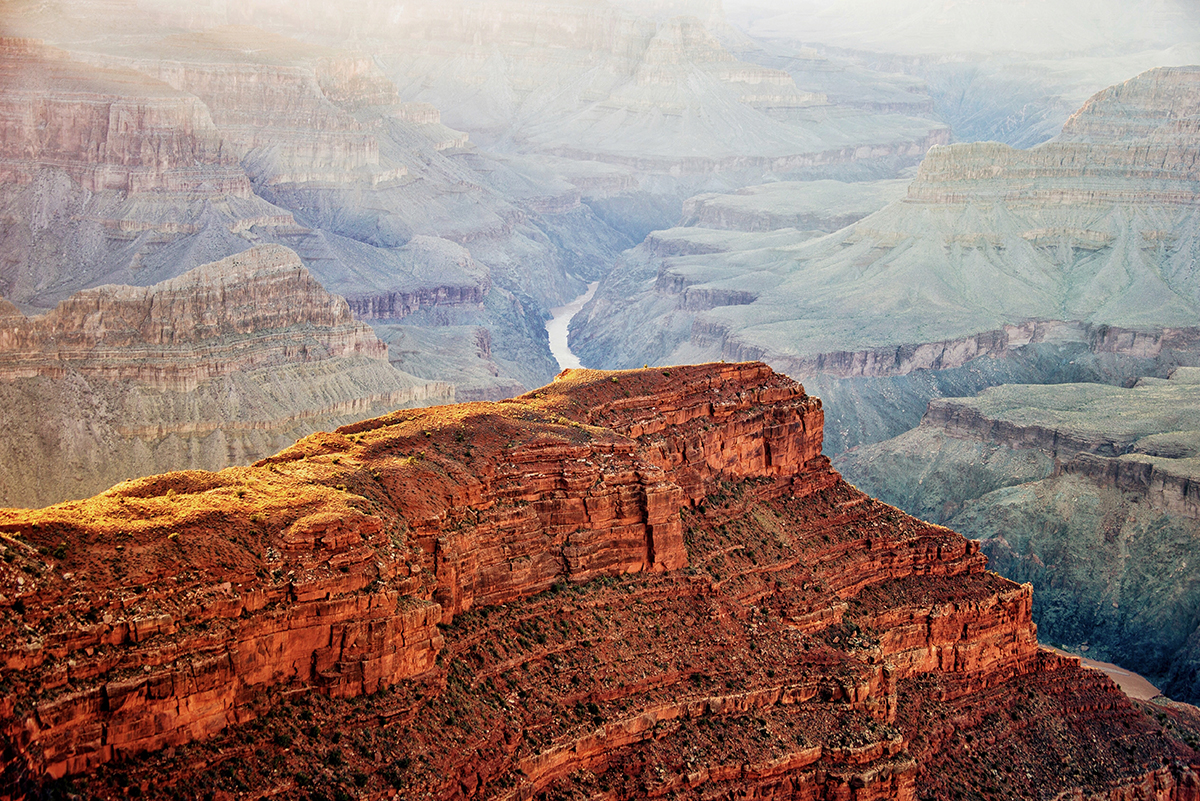 A breathtaking view of the Grand Canyon at sunset, with the vibrant colors of the sky reflecting off the canyon’s dramatic cliffs.